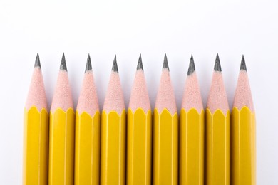 Photo of Many sharp graphite pencils on white background, top view