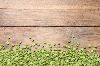 Many green coffee beans on wooden table, flat lay. Space for text