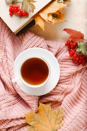 Photo of Flat lay composition with cup of aromatic tea and soft pink sweater on beige textured table. Autumn atmosphere