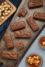 Delicious chocolate candy bars with caramel and nuts on grey wooden table, flat lay