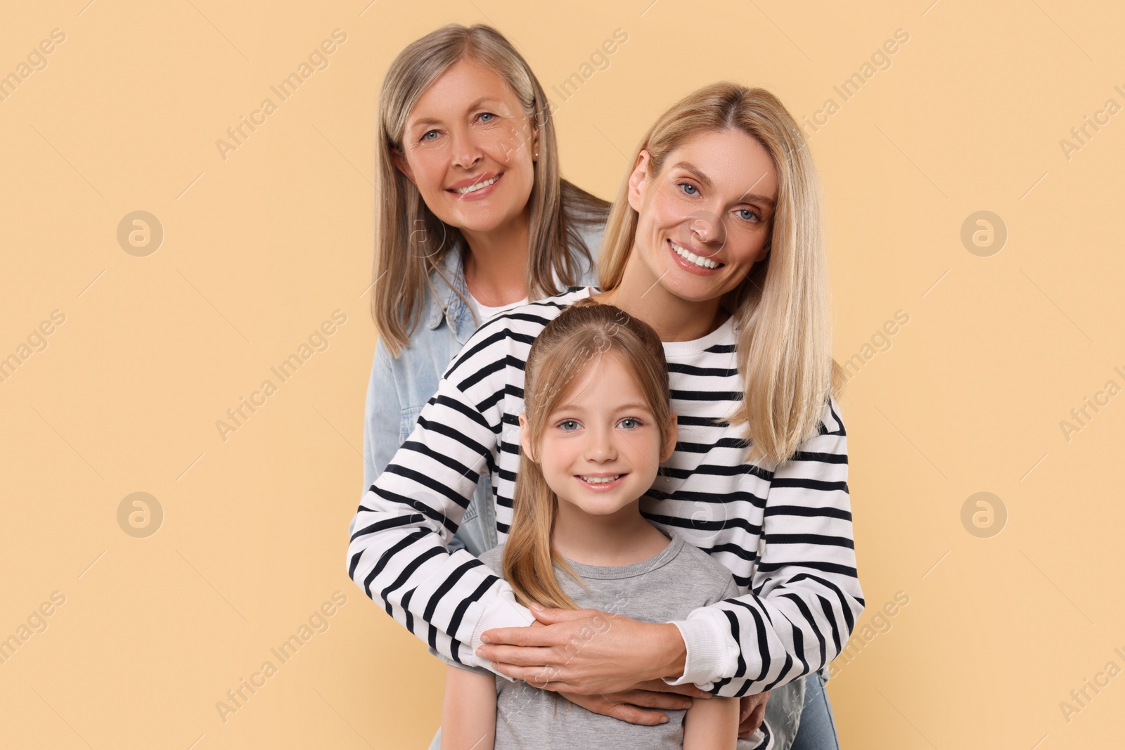 Photo of Three generations. Happy grandmother, her daughter and granddaughter on beige background