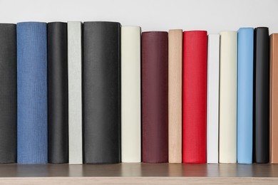 Photo of Many hardcover books on wooden table near white wall