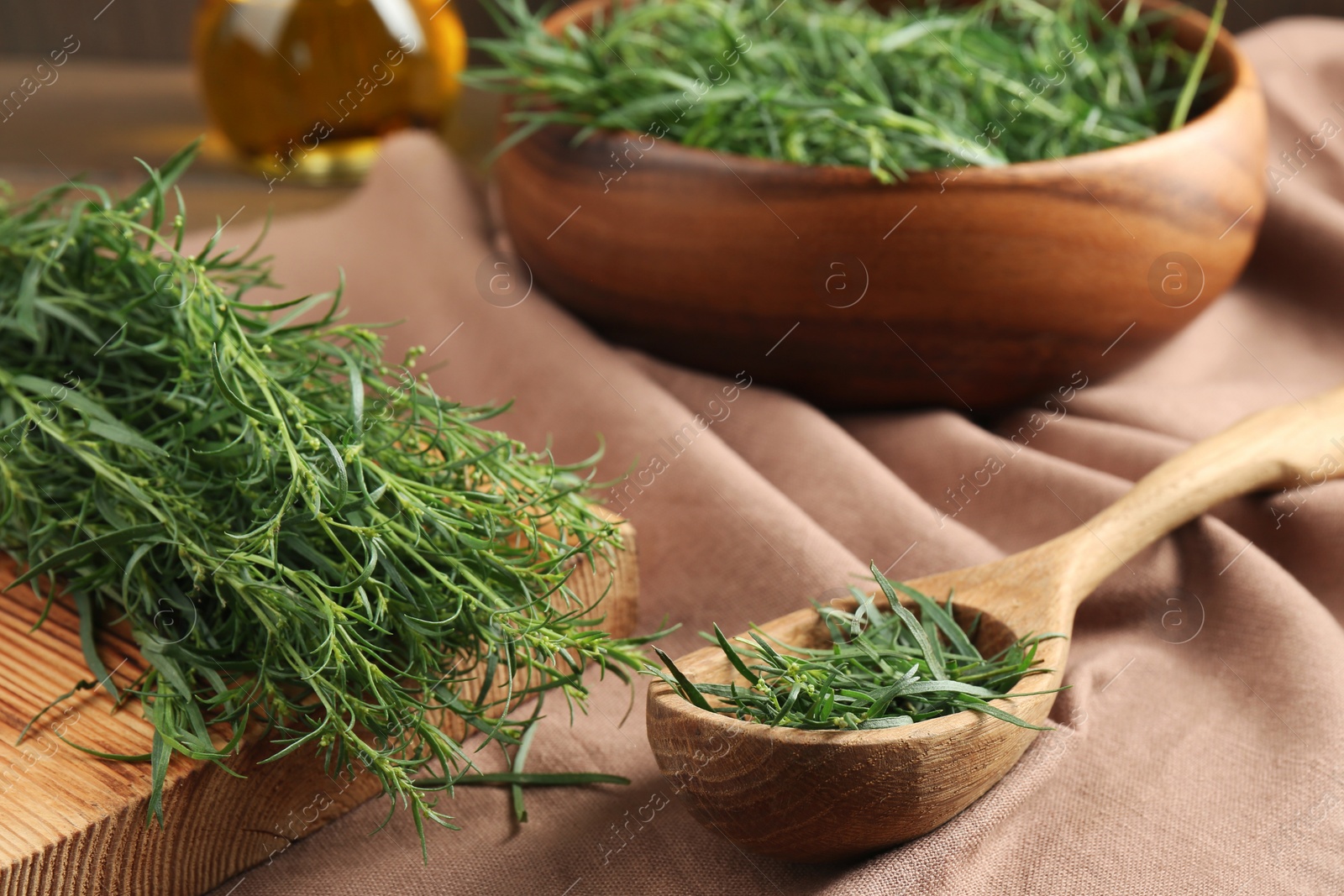 Photo of Fresh green tarragon sprigs on pink tablecloth