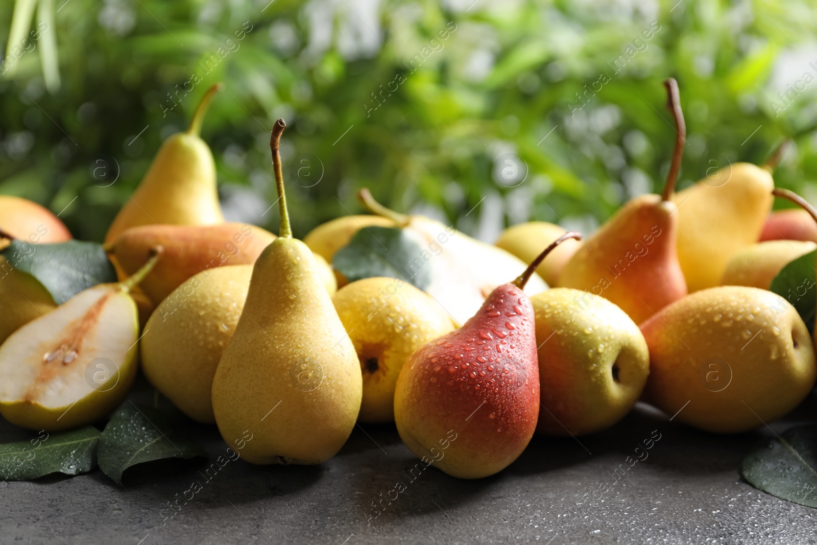 Photo of Ripe pears on grey table against blurred background