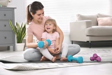 Mother and her daughter with dumbbells at home