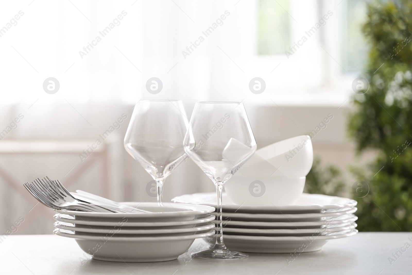 Photo of Set of clean dishware, cutlery and wineglasses on table indoors