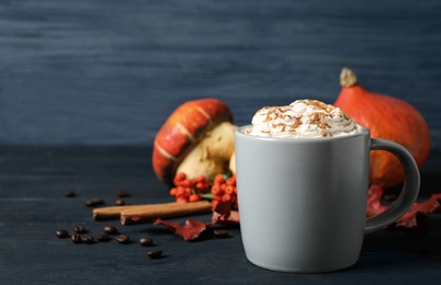 Photo of Cup with tasty pumpkin spice latte on blue wooden table