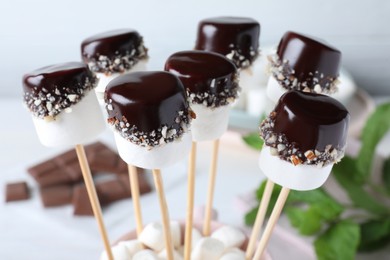 Photo of Delicious marshmallows covered with chocolate on sticks, closeup