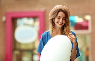 Photo of Happy young woman with cotton candy outdoors