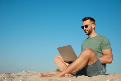 Man working with laptop on beach. Space for text