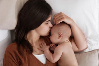 Mother with her cute baby sleeping on bed, top view