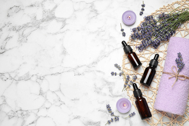 Photo of Flat lay composition with lavender flowers and natural essential oil on white marble table. Space for text