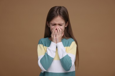 Sick girl coughing on brown background. Cold symptoms