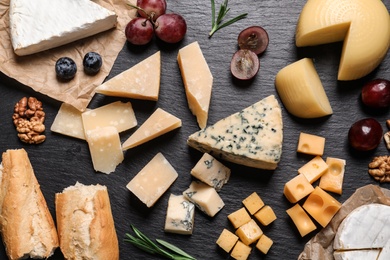 Flat lay composition with different types of delicious cheese on slate board