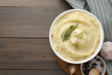 Photo of Bowl of delicious mashed potato with dill and butter on wooden table, flat lay. Space for text