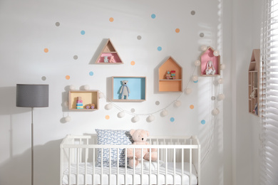 Cute children's room with house shaped shelves and crib. Interior design