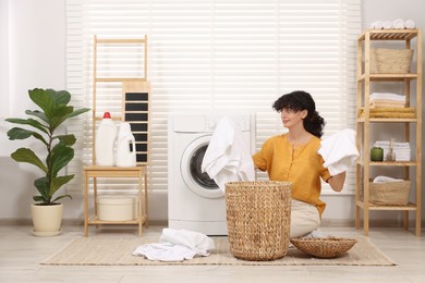 Photo of Woman with laundry near washing machine indoors