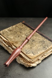 Photo of Magic wand and old book on light grey table, closeup