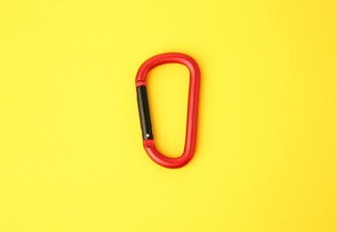 Photo of One red carabiner on yellow background, top view