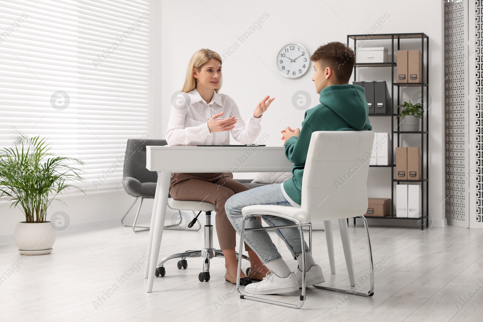 Photo of Psychologist working with teenage boy at table in office