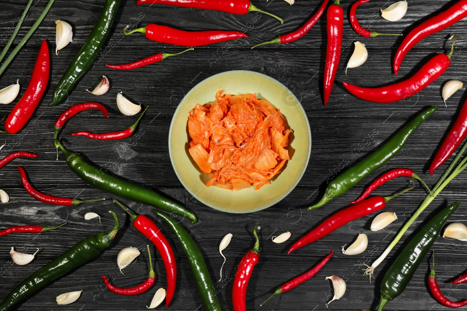 Photo of Delicious kimchi with Chinese cabbage and ingredients on black wooden table, flat lay