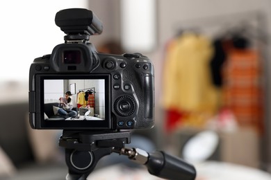 Photo of Beauty blogger recording makeup tutorial at home, focus on camera