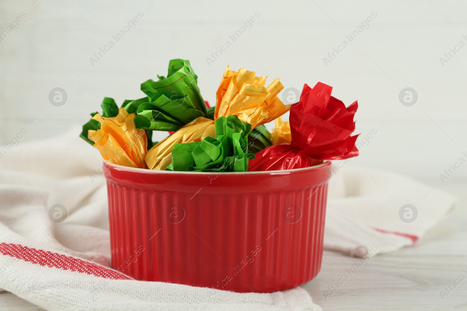 Photo of Candies in colorful wrappers on white wooden table, closeup