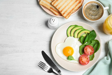 Photo of Tasty breakfast with heart shaped fried egg served on white wooden table, flat lay. Space for text