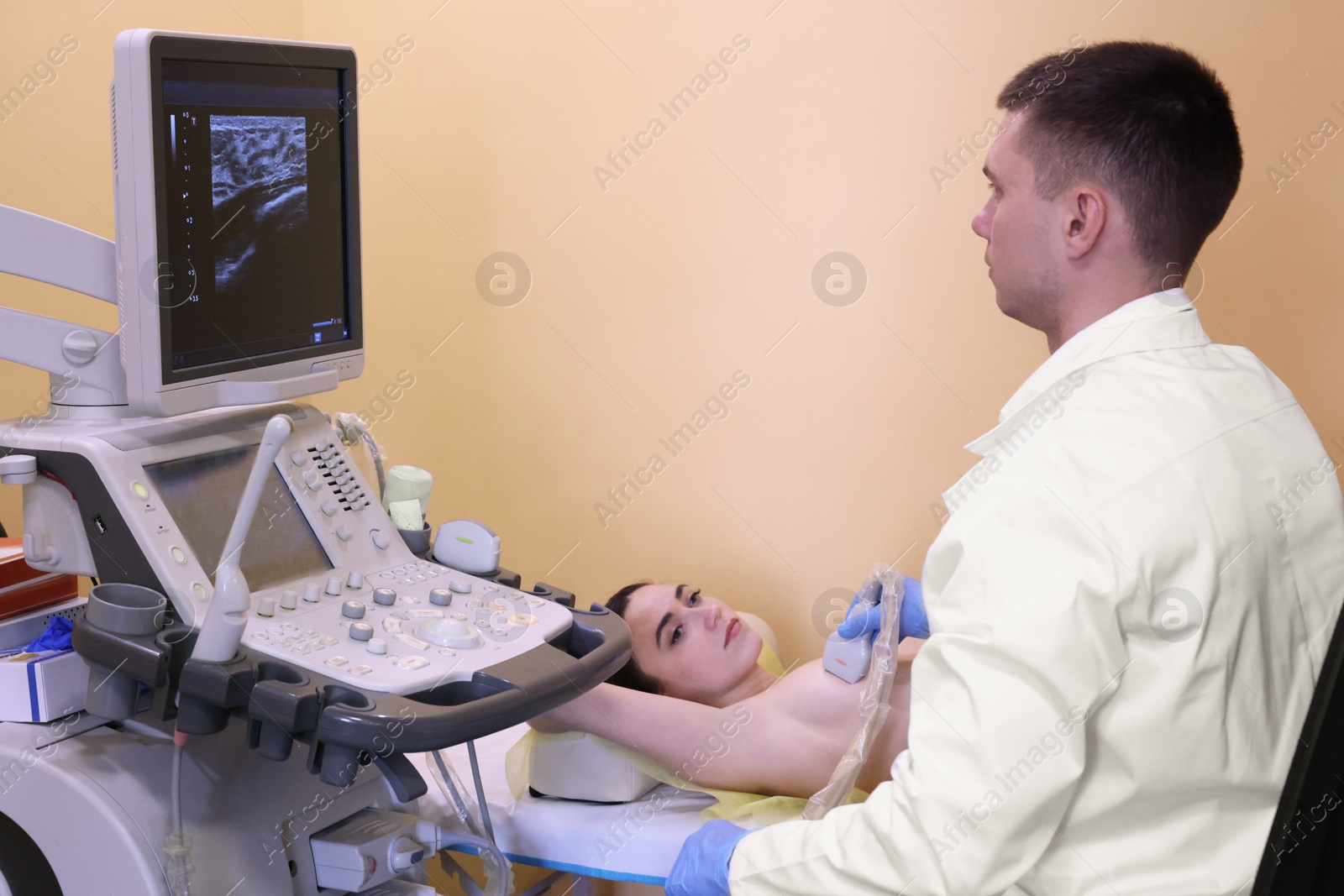 Photo of Mammologist conducting ultrasound examination of woman's breast in clinic