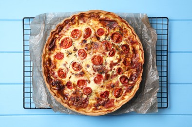 Photo of Delicious homemade quiche with prosciutto and tomatoes on light blue wooden table, top view