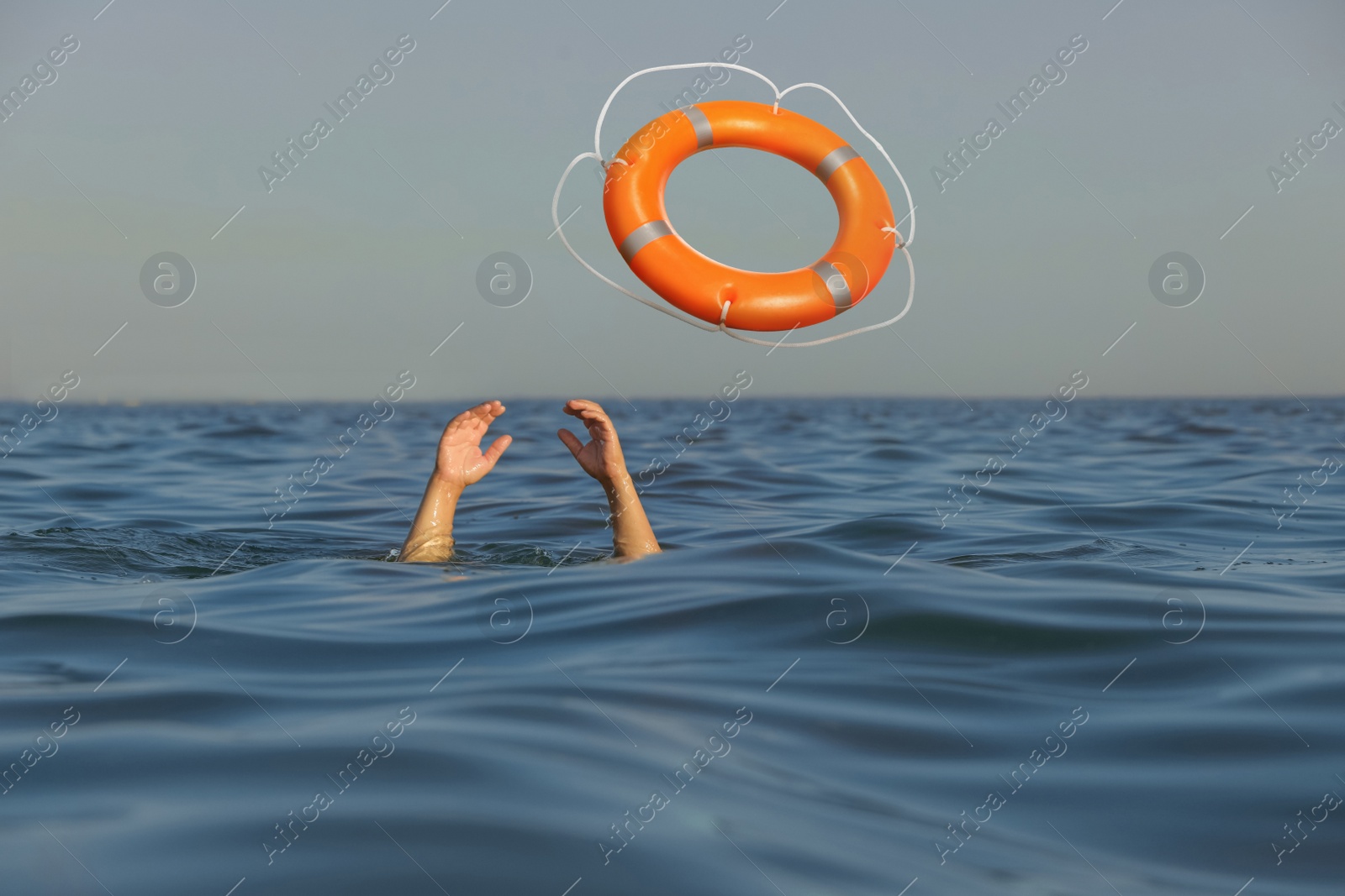 Image of Drowning man with raised hands getting lifebelt in sea