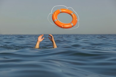 Image of Drowning man with raised hands getting lifebelt in sea