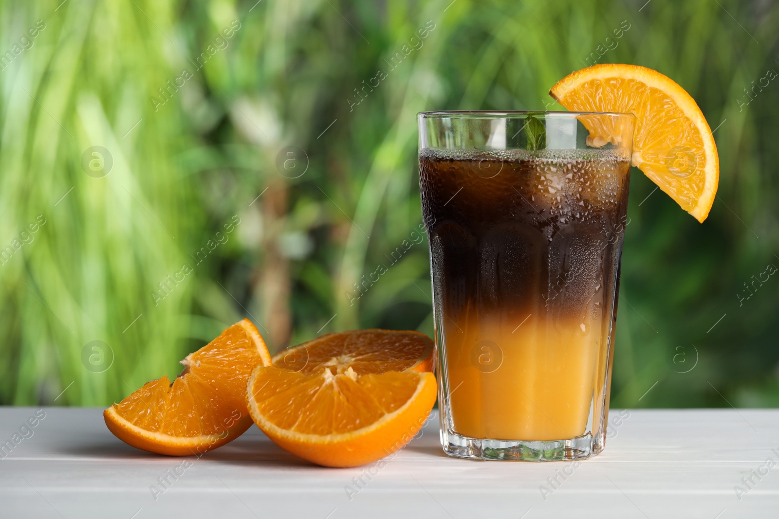 Photo of Tasty refreshing drink with coffee and orange juice on white table against blurred background, space for text