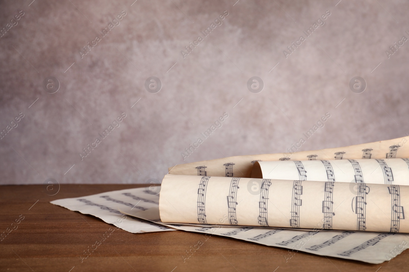 Photo of Sheets with music notes on table against color background. Space for text