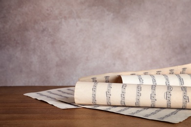 Sheets with music notes on table against color background. Space for text