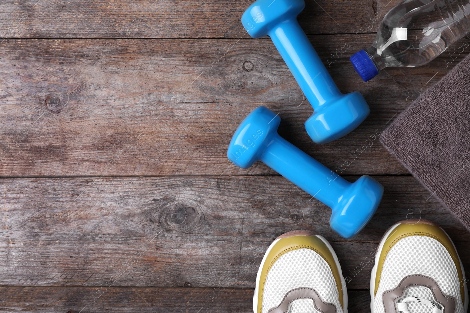 Photo of Flat lay composition with dumbbells, sneakers and space for text on wooden background