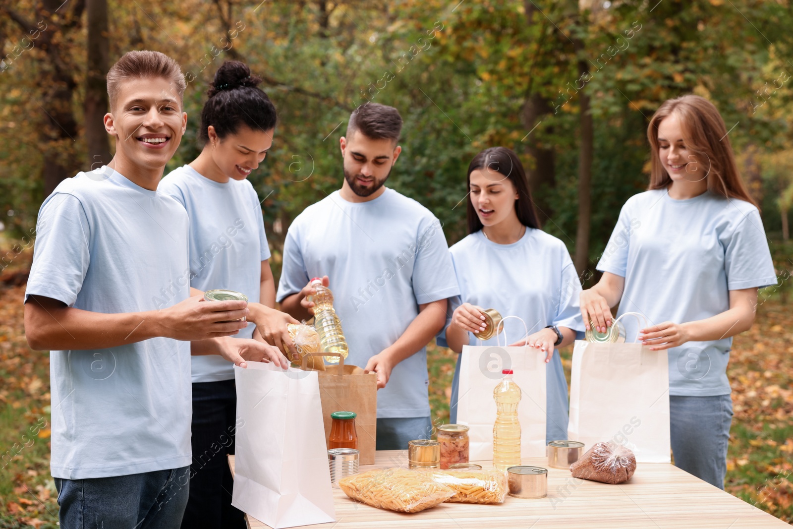 Photo of Group of volunteers packing food products at table in park