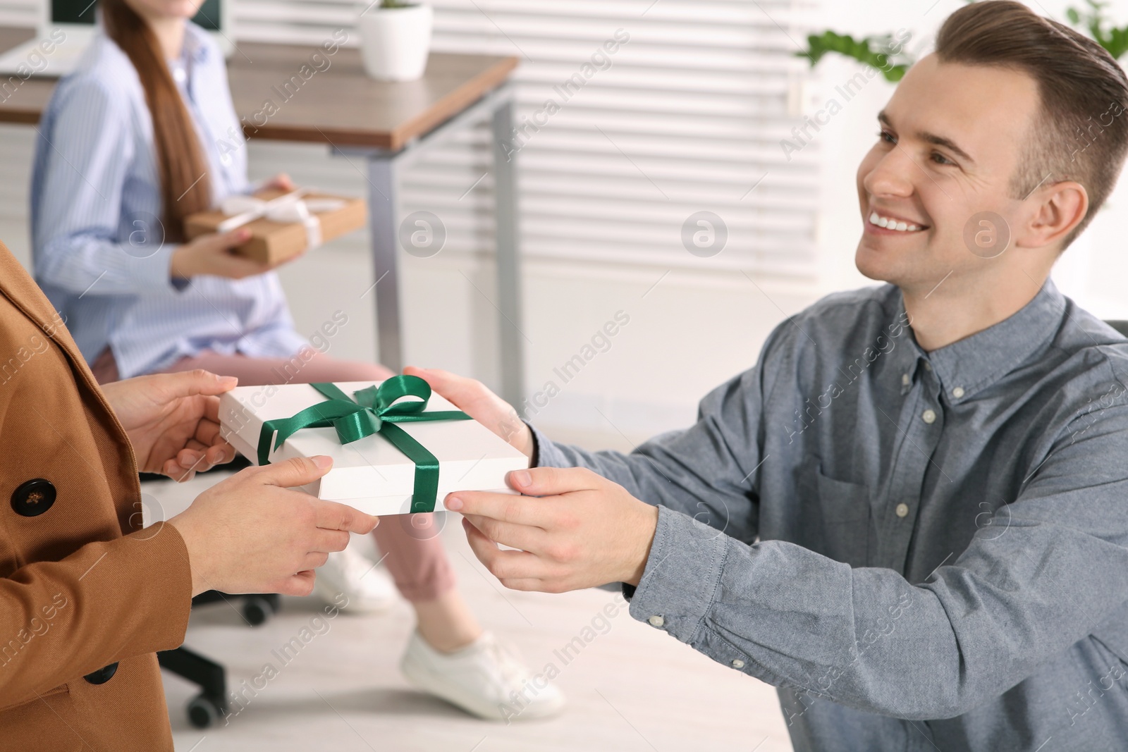 Photo of Woman presenting gift to her colleague in office