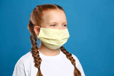 Preteen girl in protective face mask on blue background