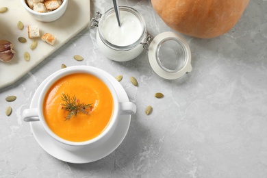 Photo of Delicious pumpkin soup in bowl on marble table, flat lay