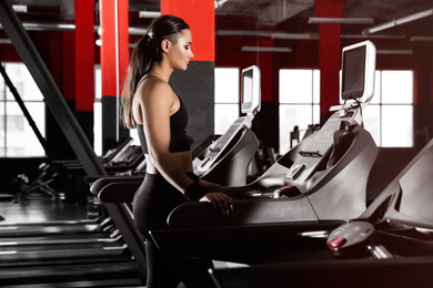 Photo of Young woman working out on treadmill in modern gym