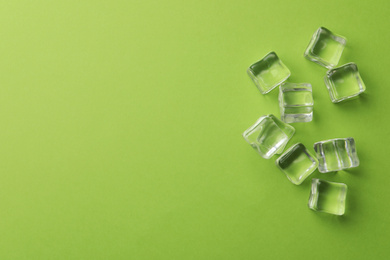 Photo of Crystal clear ice cubes on green background, flat lay. Space for text