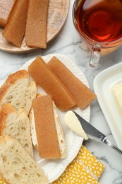 Delicious quince paste, bread and cup of tea on white marble table, flat lay