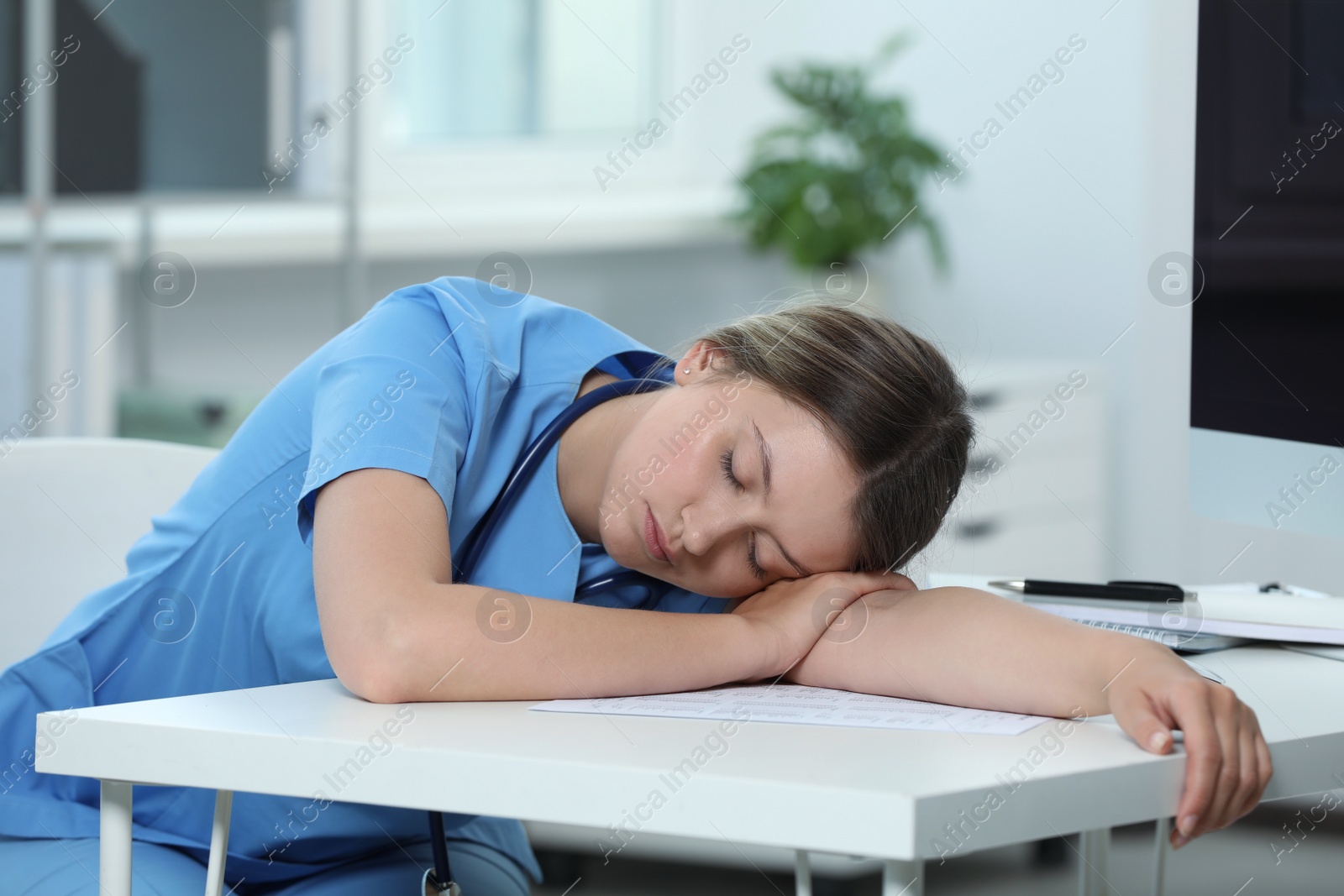 Photo of Exhausted doctor sleeping at workplace in hospital