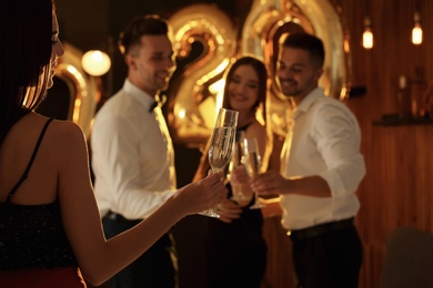 Photo of Young people celebrating New Year in club. Golden 2020 balloons on background