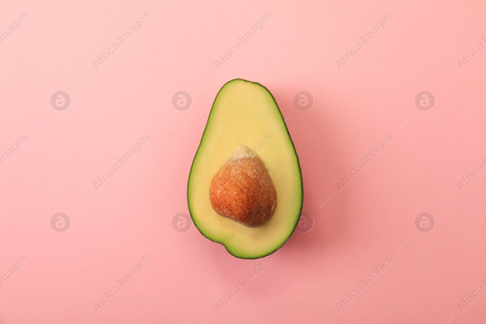 Photo of Half of delicious avocado on pink background, top view