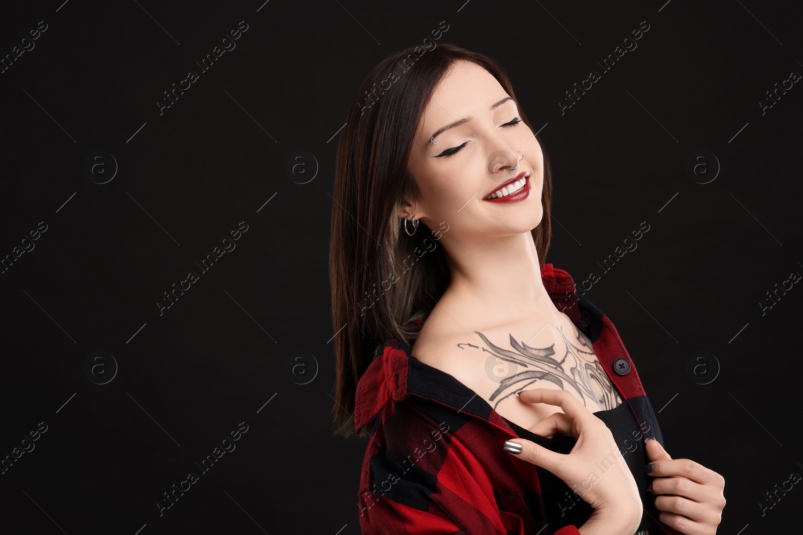 Photo of Portrait of smiling tattooed woman on black background. Space for text