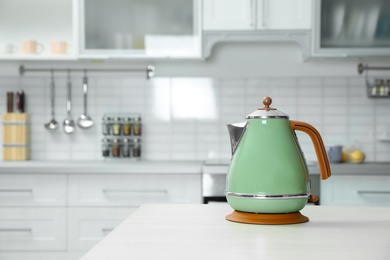 Photo of Modern electric kettle on wooden table in kitchen. Space for text