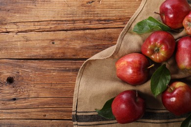 Photo of Ripe red apples with leaves on wooden table, flat lay. Space for text