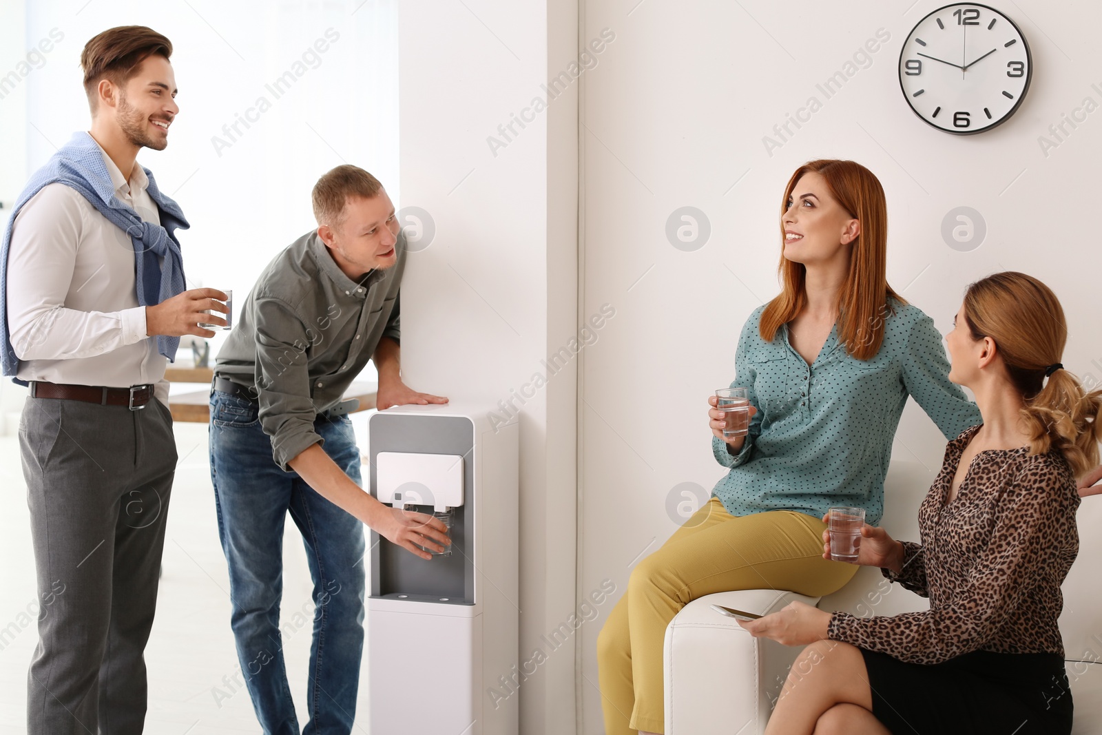 Photo of Co-workers having break near water cooler at workplace